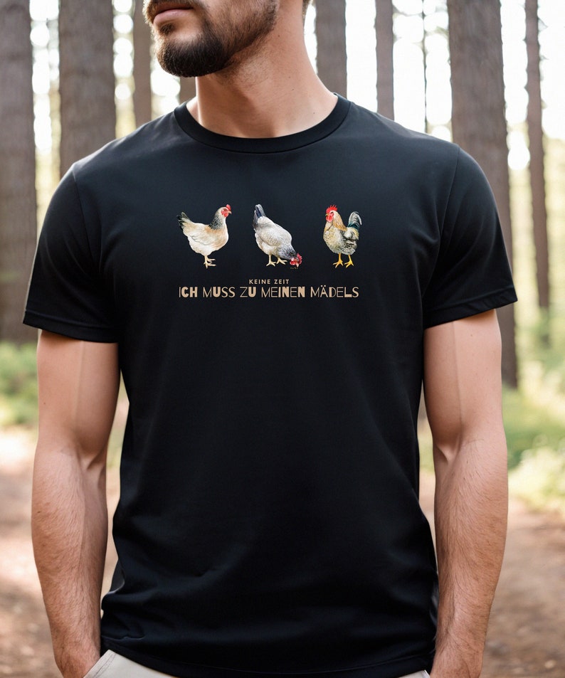 May include: A black t-shirt featuring a graphic of three chickens, two hens and a rooster. The text "Keine Zeit Ich Muss Zu Meinen M&auml;dels" is printed below the chickens.