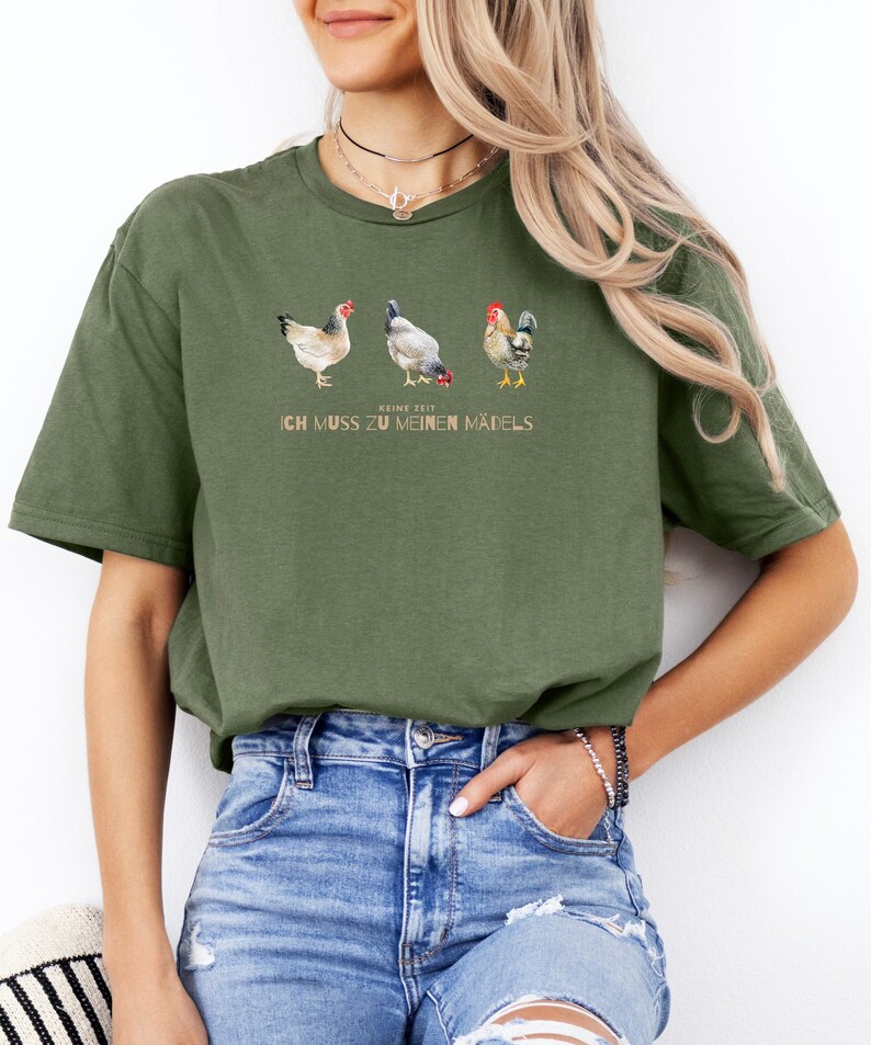 May include: A green t-shirt with a graphic of three chickens and the text "Keine Zeit Ich Muss Zu Meinen Madels".