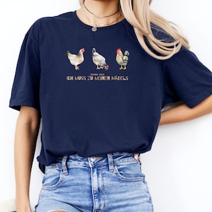 May include: A navy blue t-shirt with a graphic of three chickens. The text "Keine Zeit, ich muss zu meinen M&auml;dels" is printed on the shirt.