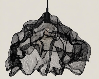 May include: A black pendant light fixture featuring a sculptural, draped mesh shade with an irregular, flowing form. The shade is suspended from a black cord and socket, with a single light bulb visible through the semi-transparent grid structure.