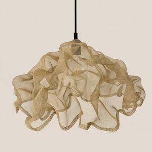 May include: A pendant light fixture featuring a gold-colored, fine wire mesh shade with a draped, organic, and layered form. The shade is suspended from a thin, black vertical rod and contains a single visible light bulb in the center.
