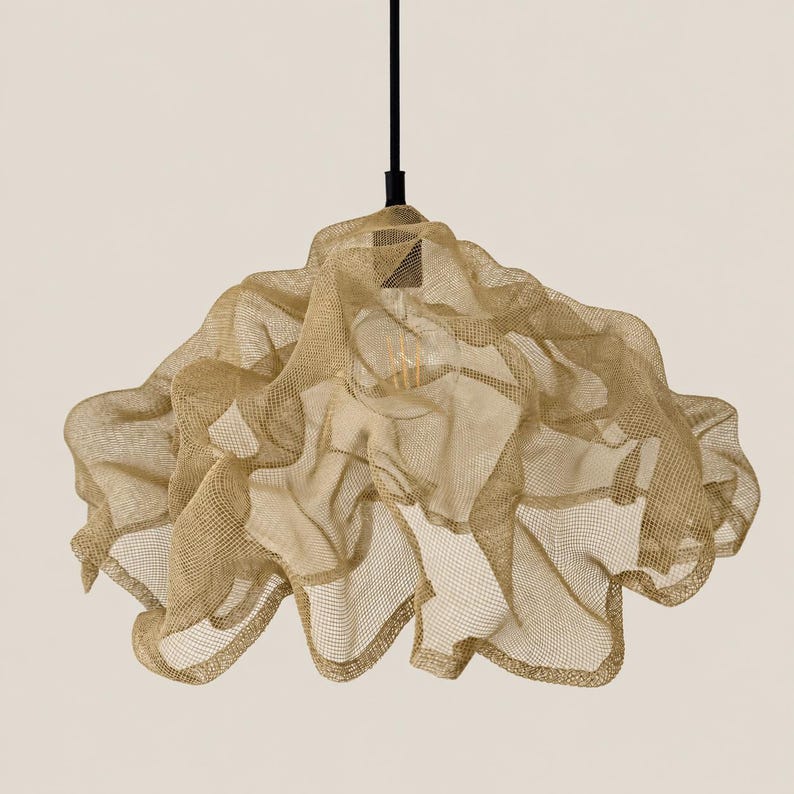 May include: A pendant light fixture featuring a gold-colored, fine wire mesh shade with a draped, organic, and layered form. The shade is suspended from a thin, black vertical rod and contains a single visible light bulb in the center.