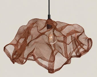 May include: A pendant light fixture featuring a copper-colored wire mesh shade with an organic, undulating shape. The shade is suspended from a thin black cord and houses a single clear glass light bulb visible through the metallic netting.