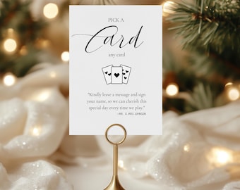 Könnte beinhalten: Weiße Karte mit schwarzem Text, der "Pick a Card, any card" lautet. Die Karte zeigt eine schwarze Illustration von drei Spielkarten mit Herzen. Der Text lautet weiter "Kindly leave a message and sign your name, so we can cherish this special day every time we play." Die Karte ist mit "MR. & MRS. JOHNSON" signiert.