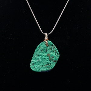 May include: A silver chain necklace with a green and blue stone pendant. The stone has a rough, textured surface.