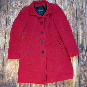 May include: A red wool coat with a black button fastening and two pockets. The coat has a classic design and is ideal for cold weather.
