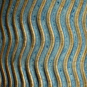 Puede incluir: Primer plano de una superficie texturizada con un patrón ondulado repetitivo. Bandas verticales alternas de marrón claro y azul con efecto marmolado. El diseño crea una apariencia tridimensional.