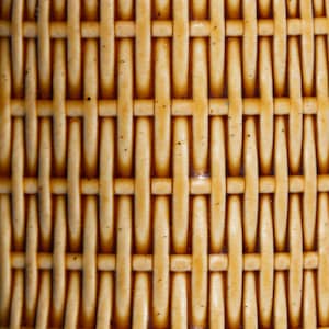 Puede incluir: Primer plano de un patrón tejido en tonos beige y marrón. El diseño presenta una textura de tejido de cesta, con bandas verticales y horizontales que crean una apariencia de cuadrícula. La superficie tiene un acabado brillante.