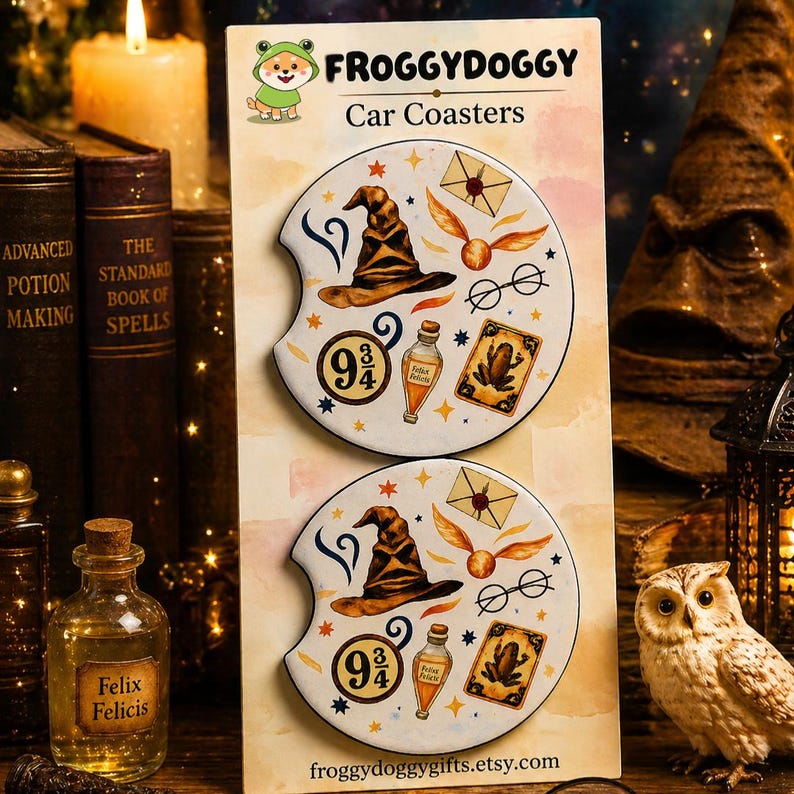 May include: Two white car coasters with a magical theme. Each coaster features a brown sorting hat, gold snitch, glasses, and a potion bottle. The coasters also have the text "9 3/4" and "Felix Felicis". The brand name "FROGGYDOGGY" is at the top.