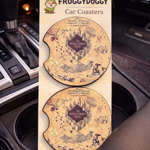 May include: Two car coasters with a map design featuring a castle and the text "The Welcomes War". The coasters are tan with dark brown illustrations and text. The brand name "FROGGYDOGGY" is at the top.