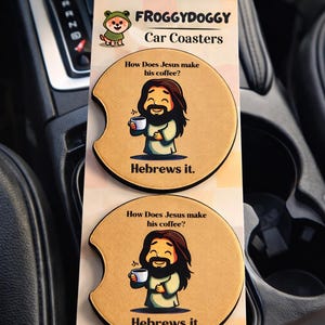 May include: Car coasters with a humorous design. The coasters feature a cartoon of Jesus holding a coffee cup, with the text "How Does Jesus make his coffee? Hebrews it." The coasters are tan with a black border and are displayed in a car.