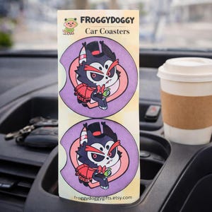 May include: Two car coasters featuring a cartoon character with a black top hat, red jacket, and bow tie. The coasters are purple and pink, with the text "FROGGY DOGGY Car Coasters" at the top. A coffee cup sits in the car's cup holder.