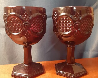 Set of 2 Avon deep ruby 1876 Cape Cod large stemmed goblets. 6&quot; tall x 3.5&quot; wide at rim. Avon mark on base. Like new with original boxes.