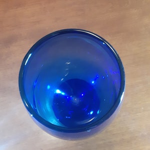 May include: A cobalt blue glass vase with a rounded bottom and a wide opening.