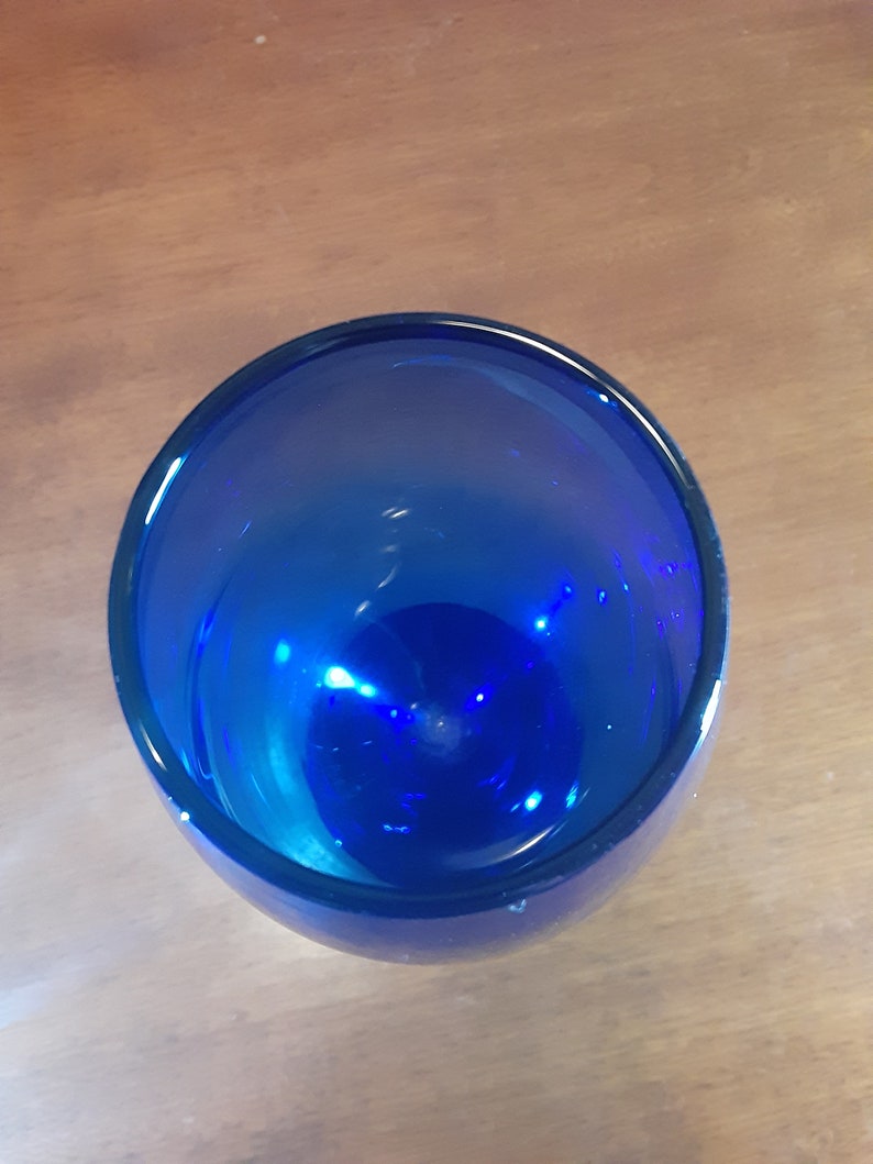May include: A cobalt blue glass vase with a rounded bottom and a wide opening.