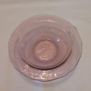 May include: A pink glass bowl with a scalloped edge and a floral design. The bowl has the words "Miss Muffet" and "Little Miss Muffet" inscribed around the rim.