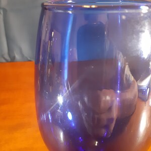 May include: A cobalt blue glass goblet with a rounded base and a wide bowl. The glass is clear and reflects light.
