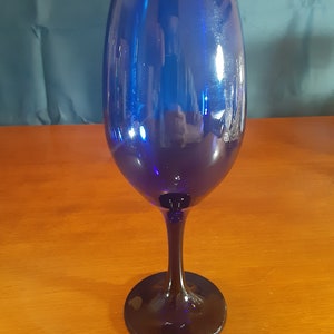 May include: A cobalt blue wine glass with a tall stem and a round base.