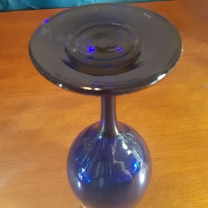 May include: A cobalt blue glass wine goblet with a wide, flat base and a tall, slender stem.