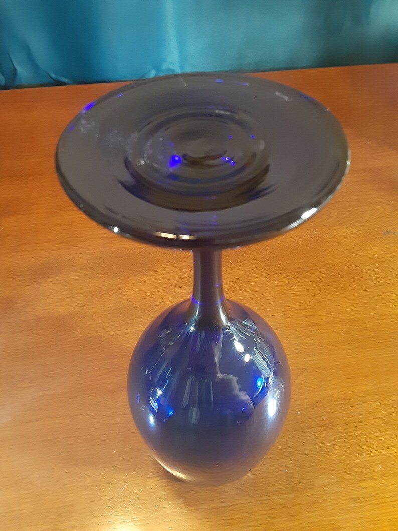 May include: A cobalt blue glass wine goblet with a wide, flat base and a tall, slender stem.