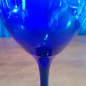 May include: A cobalt blue glass wine glass with a long stem and a wide bowl.