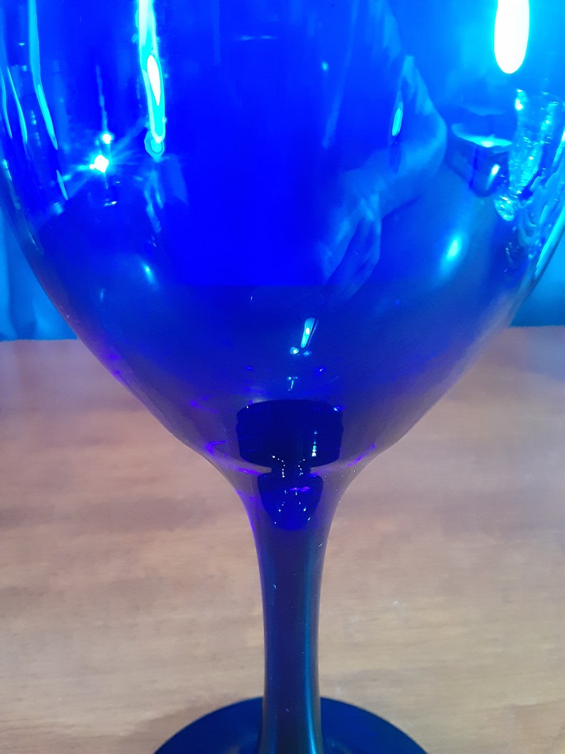 May include: A cobalt blue glass wine glass with a long stem and a wide bowl.