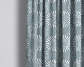 May include: A close-up of a blue curtain with a white floral pattern. The fabric has a subtle texture.
