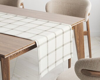 May include: A white and brown checkered table runner with a subtle woven texture. The runner is laid on a wooden table with two chairs.
