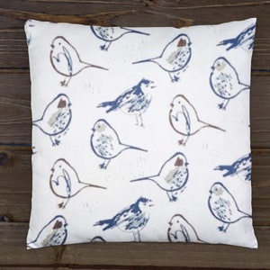 May include: A white throw pillow with a repeating pattern of blue and brown birds. The birds are drawn in a simple, stylized manner.