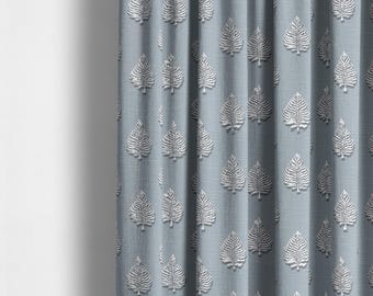 May include: A close-up of a blue curtain with a white leaf pattern. The fabric has a subtle texture.