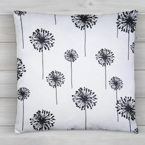 May include: White pillow with a black and white dandelion print. The dandelions are stylized and have a simple design.