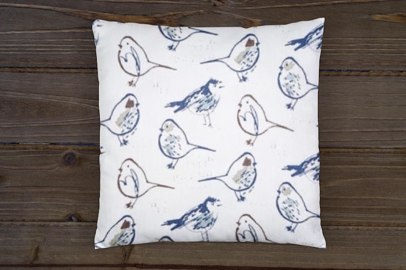 May include: A white throw pillow with a repeating pattern of blue and brown birds. The birds are drawn in a simple, stylized manner.