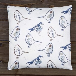 May include: A white throw pillow with a repeating pattern of blue and brown birds. The birds are drawn in a simple, stylized manner.