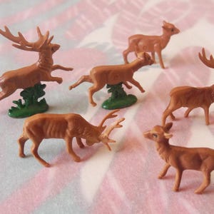 May include: A set of six brown plastic deer figurines. The deer are in various poses, including standing, running, and leaping. The figurines are all about 3 inches tall and are made of a durable plastic.