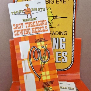 May include: An orange and white package of "Paces Big Eye" easy threading sewing needles. The package features a camel logo and text that reads "Easy Threading Sewing Needle." The display also includes a diagram of a needle and thread.