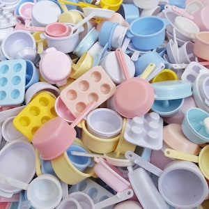 May include: A collection of colorful miniature kitchen cookware, including pots, pans, and baking dishes. The set features a variety of shapes and sizes, with some pieces having a textured or patterned surface.