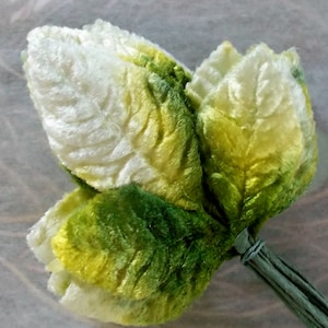 May include: A bouquet of artificial flowers made of velvet fabric. The flowers are a gradient of white, yellow, and green.