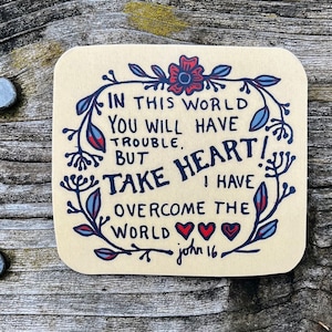 May include: A beige square sticker with a floral border and the text "IN THIS WORLD YOU WILL HAVE TROUBLE. BUT TAKE HEART! I HAVE OVERCOME THE WORLD john 16."