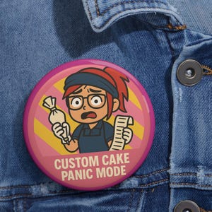 May include: A round, pink button with the text "CUSTOM CAKE PANIC MODE" features a cartoon baker holding a pastry bag and a long order list. The baker has red hair, glasses, and a worried expression. The background has yellow and pink stripes.