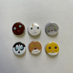 Könnte beinhalten: Sechs runde Knöpfe mit verschiedenen Tiergesichtern. Die Knöpfe sind weiß mit schwarzen Umrissen und zeigen einen braunen Hund, eine weiße Katze, eine graue Katze, einen braunen Hund, einen schwarz-weißen Husky und einen gelben Hamster.