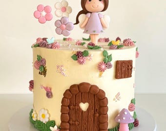 May include: A white cake decorated with a purple fairy figurine, flowers, and a small brown door. The cake is on a white cake stand.