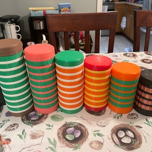 May include: Six colorful stacking toys with different patterns and colors. The toys are made of plastic and have a cylindrical shape. The colors are brown, pink, green, orange, and black.