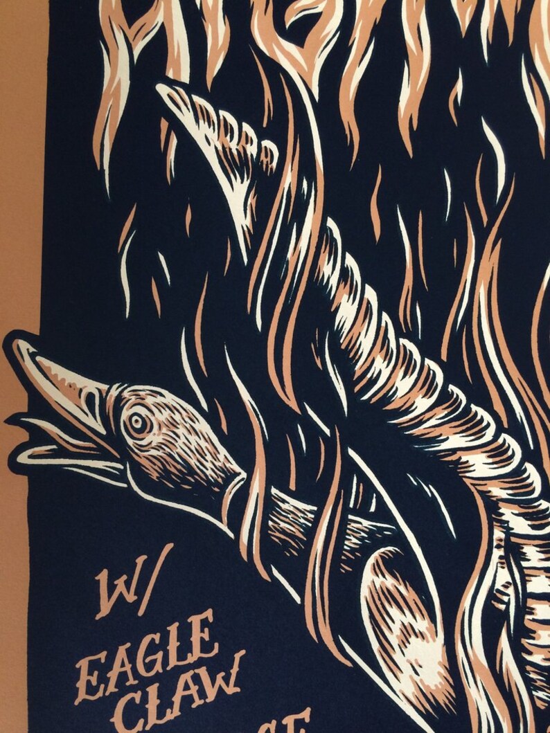 May include: A graphic art print featuring a stylized eagle claw design with flames. The artwork uses a palette of dark blue, beige, and off-white. The text "W/ EAGLE CLAW" is visible in the lower left corner.