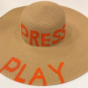 Custome hand painted straw hat with orange writing “ press play”