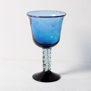 May include: A blue glass goblet with a twisted stem and a black base.