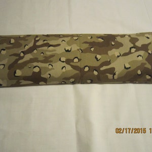 May include: A long, rectangular brown and tan camouflage-patterned fabric pillow.