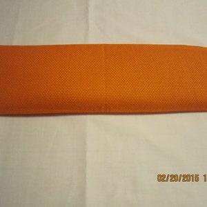 May include: Orange fabric rectangular pillow with white polka dots.