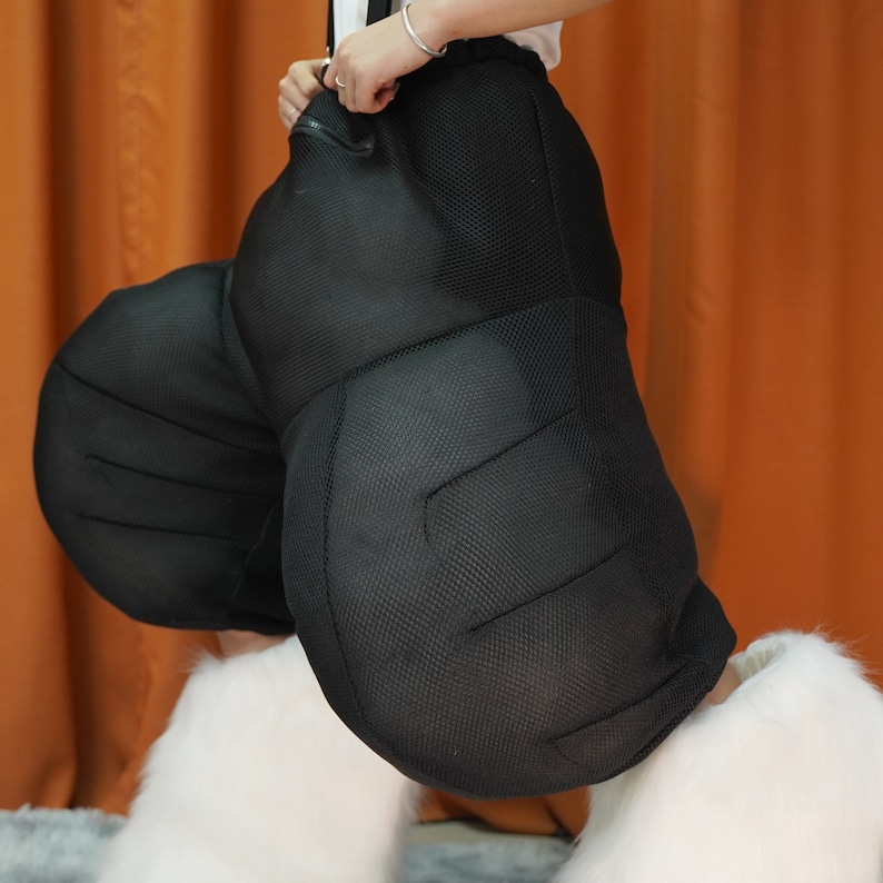 May include: A black mesh jumpsuit with padded legs, worn with white fur leg warmers.
