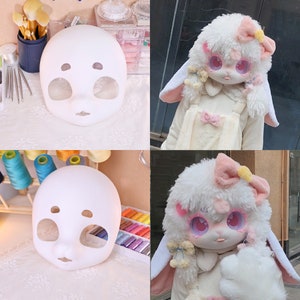 May include: Two white blank doll heads with painted eyes and mouths. The doll heads are on a white surface. The doll heads are for crafting and customizing.