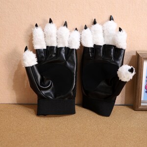 Puede incluir: Un par de guantes de piel sint&eacute;tica negra con garras de piel sint&eacute;tica blanca. Los guantes tienen una banda el&aacute;stica negra en la mu&ntilde;eca.